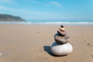 Pyramid of stones for meditation lying on sea coast. Five colored stones tower. Simple poise stones. Simplicity harmony and balance, rock zen sculptures. Zen and relax concept. 
