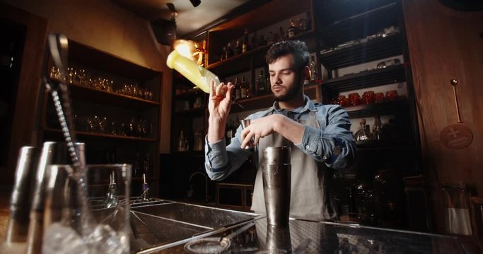 Professional bartender masterly creating a cocktail in modern bar. Experienced barman adding syrip into shaker using jigger - food and drink, nightlife close up 4k footage