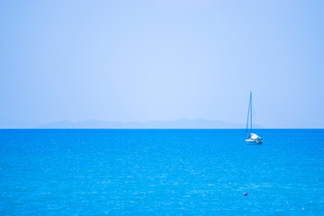 Fototapeta na wymiar blue sea with white boat and island in the background