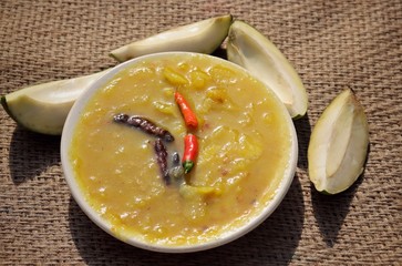 Closeup of Mango Chutney Cuisine in a Plate with Raw Mango on Burlap Background