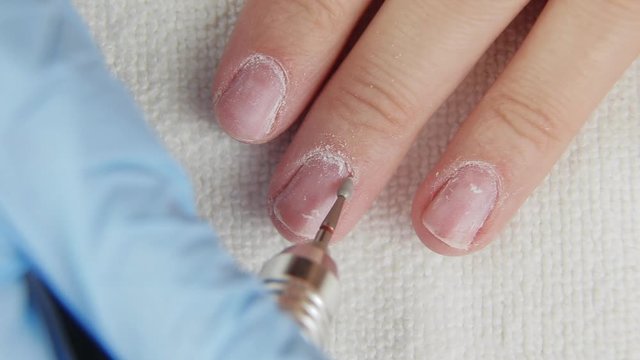 Young woman removes gel shellac polish from nails using manicure machine