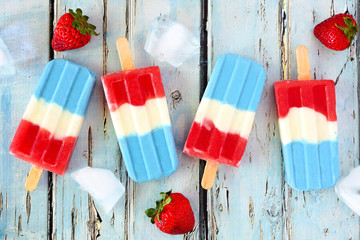 Red, white and blue summer fruit ice pops. Top view on a rustic blue wood background.
