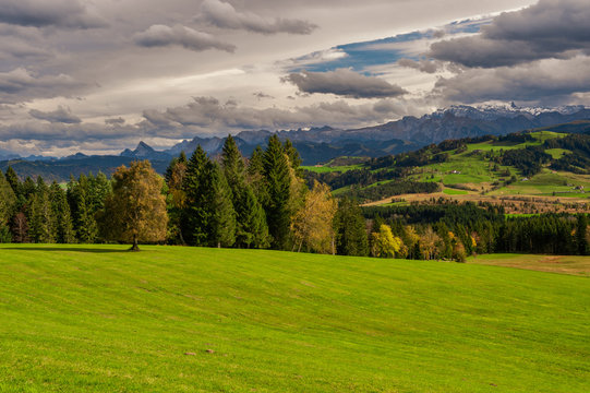 The view of the Raten mountain pass in Central Switzerland.
Typical tranquil Swiss landscape with pastries, hills, forests and Alpine mountain range in the background