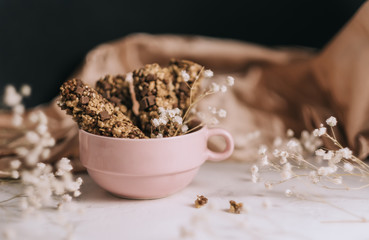 Sweet dessert, chocolate bar in a pink cup, decorated with white gypsophila flowers.