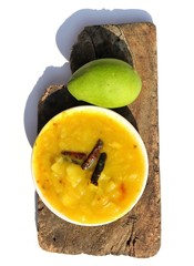Mango Chutney or Dish in a Plate with a Raw Mango on Wooden Piece with White Background