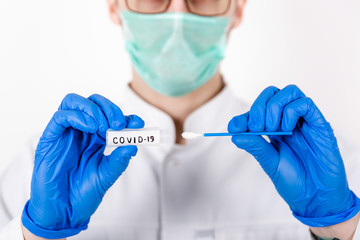 A healthcare professional takes a smear of COVID-19. Wear a white robe, gloves made of a protective mask. Test tube for analysis. Doctor with test tube for analysis and sampling of infection.