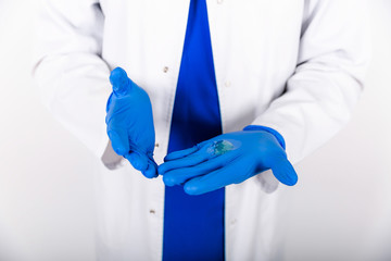 Treatment of blue rubber gloves with an antiseptic against bacteria. The doctor uses an antiseptic...