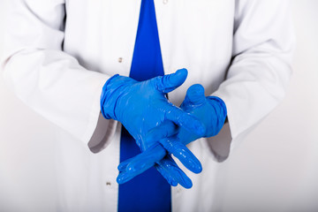 Treatment of blue rubber gloves with an antiseptic against bacteria. The doctor uses an antiseptic...