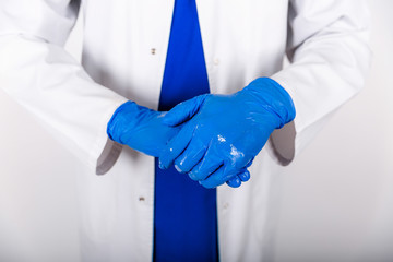 Treatment of blue rubber gloves with an antiseptic against bacteria. The doctor uses an antiseptic with blue gloves. Doctor in a white coat and protective gloves. The use of a disinfectant with gloves