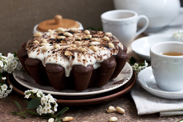 Chocolate cake with peanuts on table with tea and flowers
