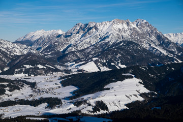 Mountains of mountain range Wilder Kaiser at Fieberbrunn in winter with snow, forest and valley, clouds in the sky, Tyrol Austria.