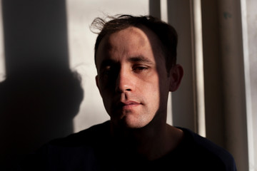 Portrait of a guy in natural light. The face of supper in the early morning. European type of face. Brown eyes and sleepy face. A simple moment of life. Adult man looking at the camera.