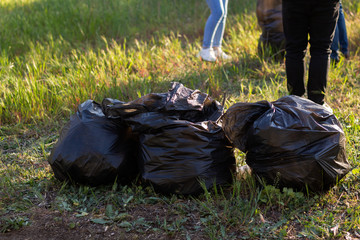 people holding a plastic garbage bottle put in a garbage bag for cleaning