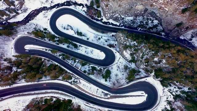 Aerial drone view of a serpentine in rocky mountain forest, Bicaz gorge with winding road in winter season,Cheile Bicazului, Romania