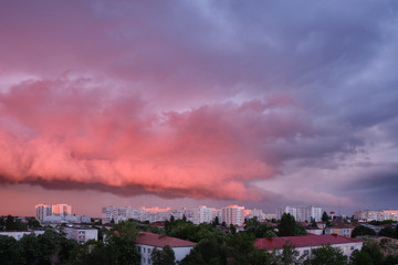 Pink and purple storm clouds at sunset, in Bucharest, Romania, contrasting with bright exterior buildings.