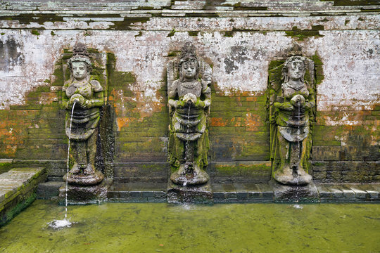 pool with golden carp and statues of women in the Goa Gajah temple complex