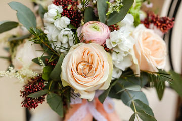 Close up two gold wedding rings lie in the bride's bouquet in flowers