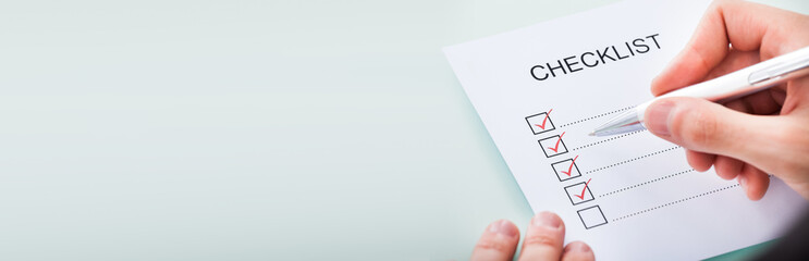 Person's Hand Marking On Checklist With Pen