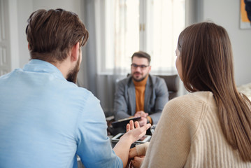 Young unhappy couple on special marriage therapy session with professional therapist. Qualified...