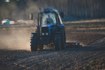 Tractor with a disc harrow system harrows the cultivated farm field, process of harrowing and...