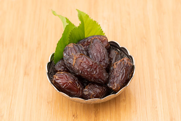 Palm dates on the silver plate, wooden background.
