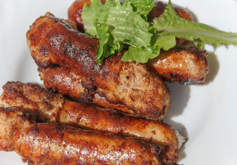   cooked on fire small sausages close-up in a white plate 