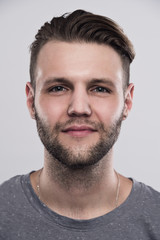 Close up portrait of serious gloomy bearded man with stylish hairstyle posing against white background