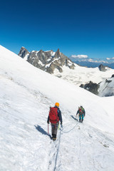 Alpinists with rope and climbing tools on Col du Midi in front of Grandes Jorasses, Mont Blanc massif in the French Alps, Chamonix Mont-Blanc, France