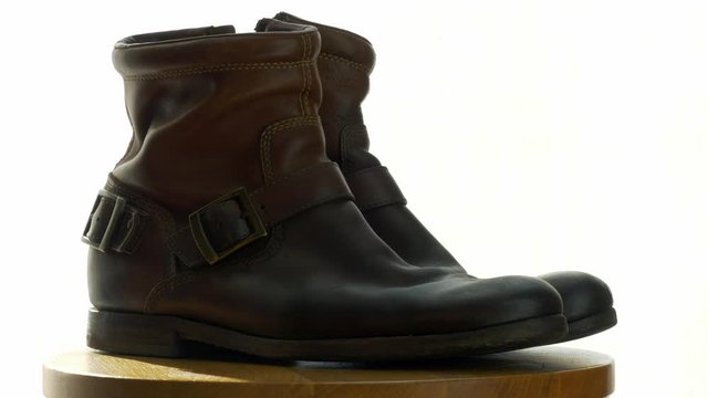 A man cleans old shoes on a wooden chair with a Shoe brush to wash away dust and dirt.