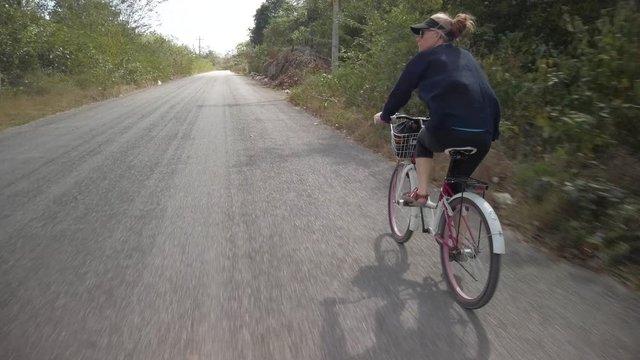 Steadicam Following To The Side Of A Mature Woman On Beach Cruiser Bicycle Riding On The Road In Valladolid, Mexico.