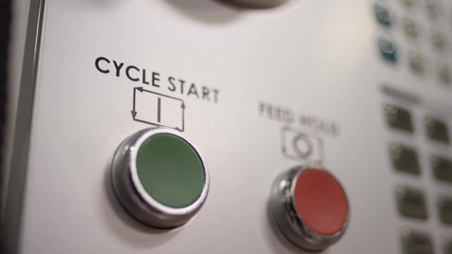 Close up finger press start button on mold machine in manufacturing plant
