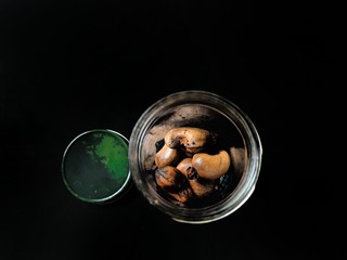 Baked cashew seeds in a glass jar on black background. healthy food concept