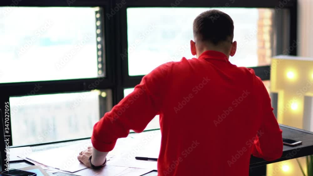 Poster smart young man dressed in red sweater updating software on modern laptop computer using wireless in