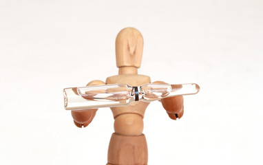 Wood figurine holding a clear vaccine vial