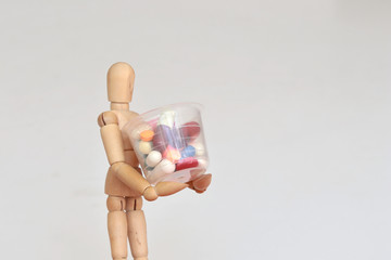 Wood figurine carrying plastic container with drugs