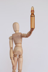 Brown vaccine vial in the hand of wood figurine