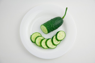 sliced green fresh cucumber on a white plate and white isolated background
