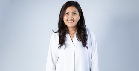 Portrait of Young Asian pretty cute cheerful business woman keeping arms crossed and smiling close up and looking at camera on white background. natural make-up, and white teeth