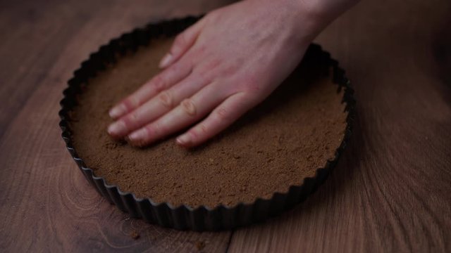 A ready base flat layer made from fine powder from biscuits/cookies for a Chocolate cake in a non-stick cake pan.
