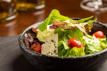 Salad with green lettuce and green leaves with blue cheese and tomatoes on a bowl