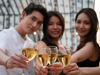 Group of asian friend cheering and drinking at terrace party. Young people toasting glass with wine at rooftop restaurant. Friendship ,youth lifestyle and nightlife concept.