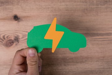 Sign of the electricity on the papercut of a car in the hands of a man