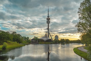 The rising morning sun illuminates dramatic clouds over the Munich Olympic Park