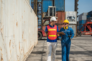 Foreman and dock worker staff working checking at Container cargo harbor holding clipboard. Business Logistics import export shipping concept.