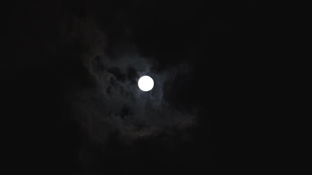 super moon in the night sky with thick dark clouds passying by in front of it, real time speed
