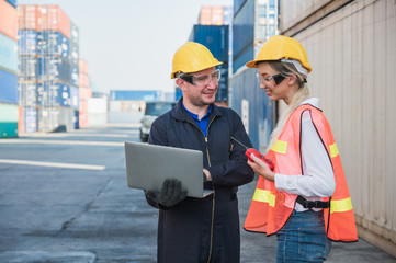 Two foreman man & woman worker working checking at Container cargo harbor holding laptop computer...