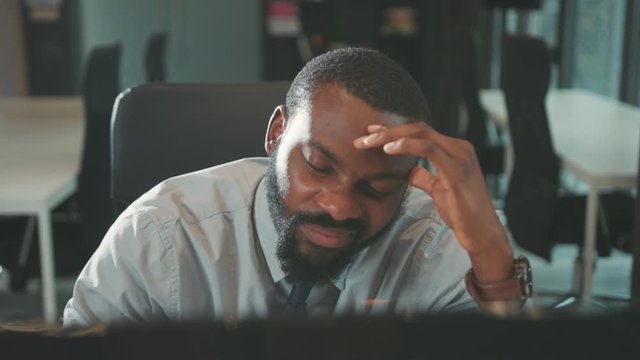Sick African American handsome man uses computer for work feel headache in modern office programmer looks at monitor screen successful worker businessman slow motion