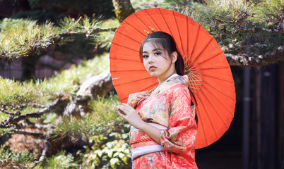 Asian woman tourists. Japanese girl wearing a kimono holding a red umbrella. Beautiful girl wearing traditional japanese kimono in Tsumago juku is now popular in village at Nagano Prefecture, Japan.