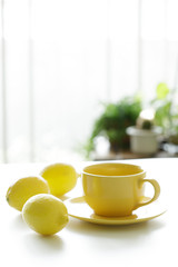 cup of tea with fresh yellow lemons on white background