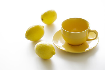 cup of tea with fresh yellow lemons on white background